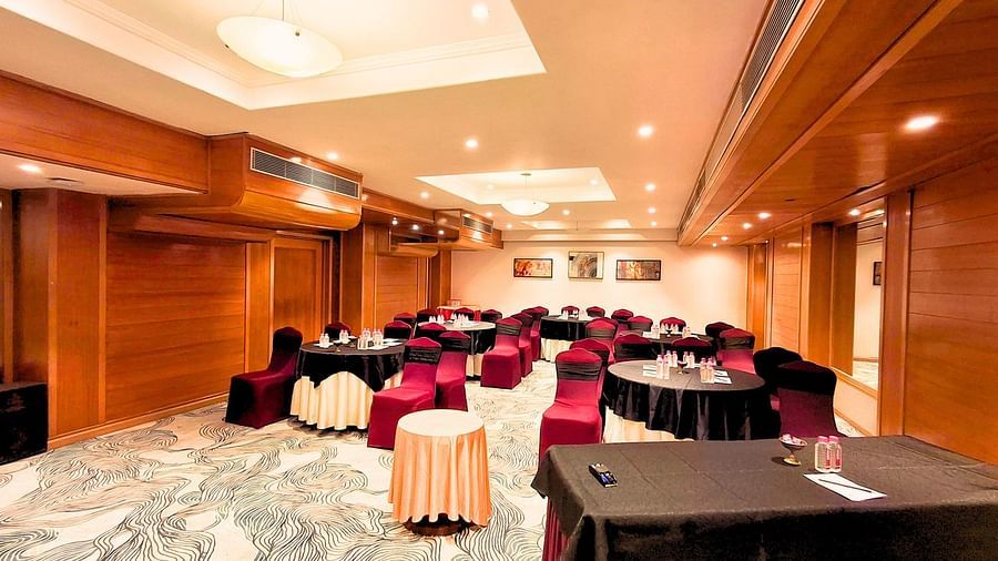 A well-lit conference room at Pride Plaza Ahmedabad, featuring a U-shaped arrangement of tables with red tablecloths, suitable for meetings and presentations.
